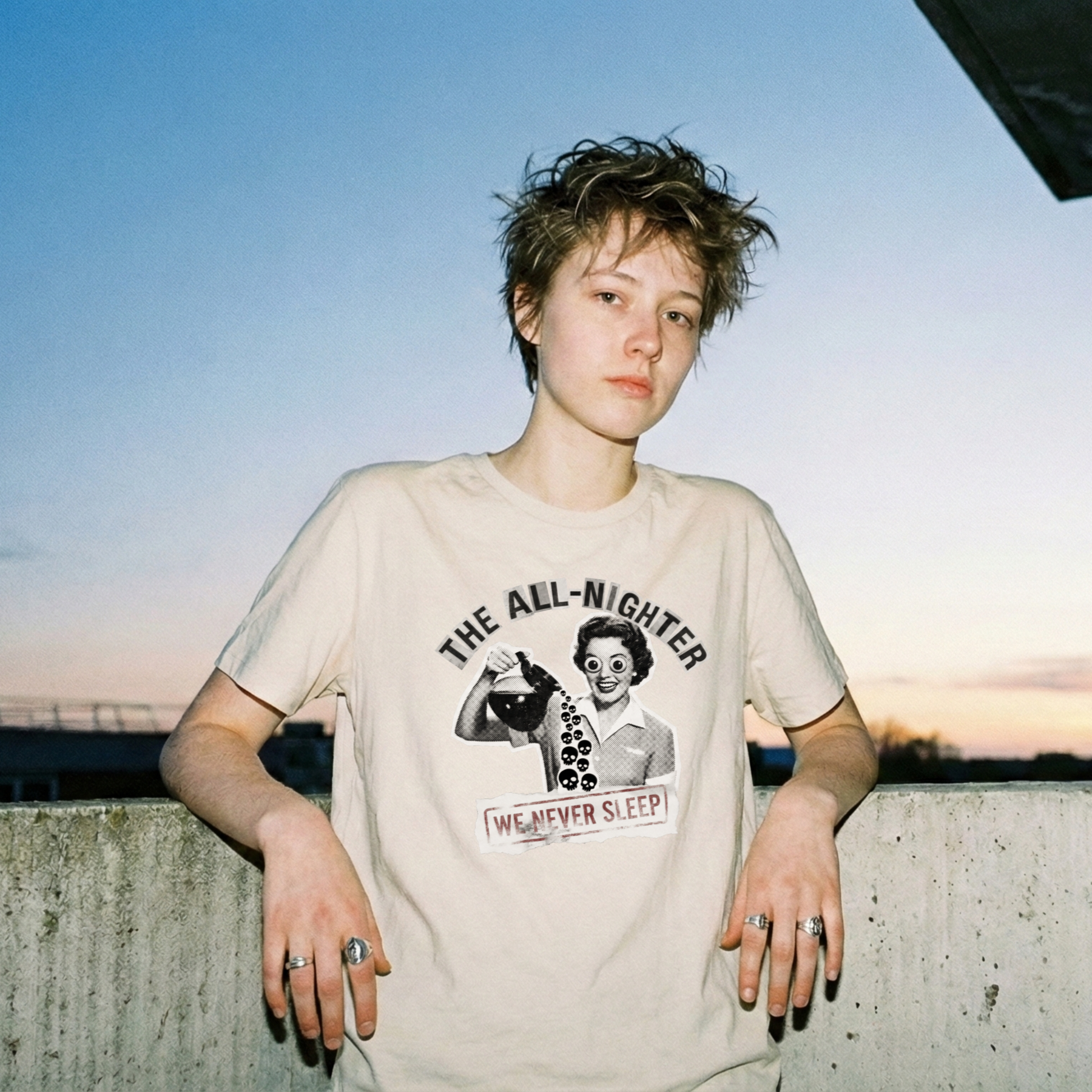 Collage art t-shirt featuring a retro 50s housewife pouring coffee made of skulls. Text reads The All-Nighter We Never Sleep.