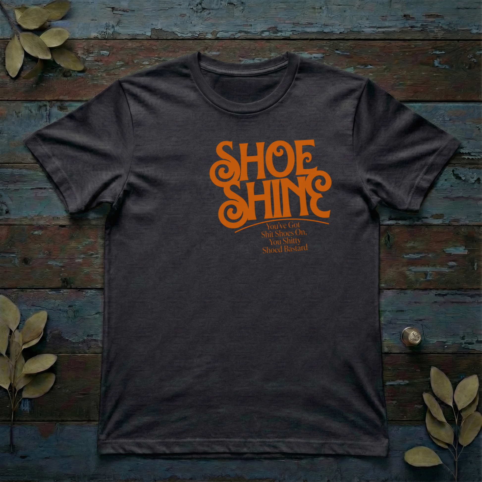 Retro orange typography on an organic t-shirt reading Shoe Shine and a funny British insult.